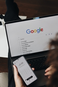 A person holding a cell phone and a laptop