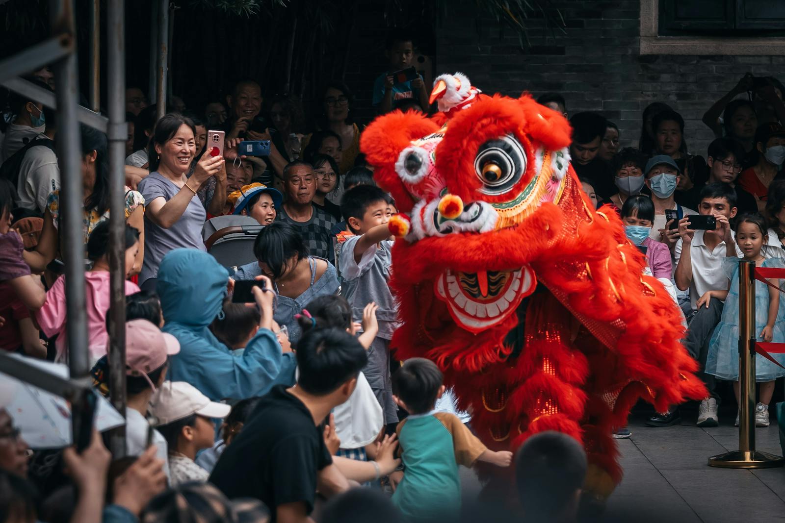 Colorful lion dance performance attracts excited crowd during street celebration.