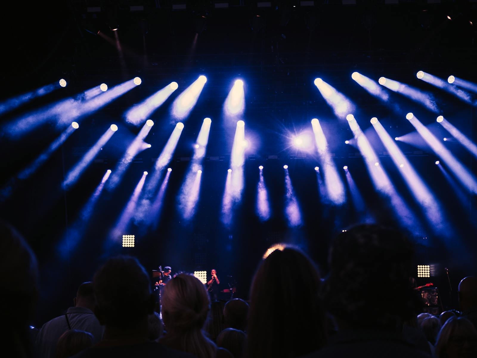 Lively crowd enjoying a concert with stunning stage lights and atmospheric ambiance.