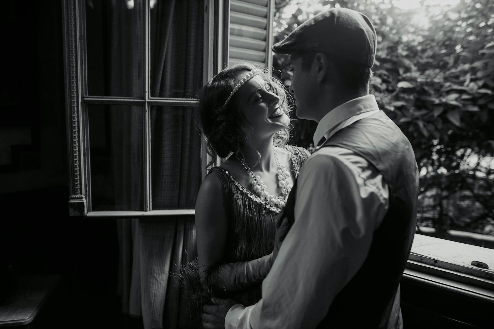 Charming black and white shot of a vintage-styled couple sharing a moment by a window in Buenos Aires.