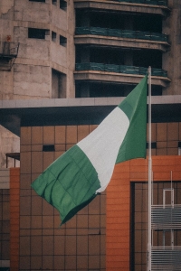 Nigerian flag fluttering against a modern city building backdrop, symbolizing national pride.