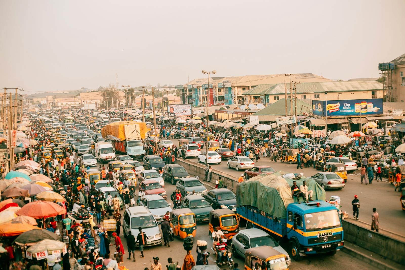 A busy street market scene with heavy traffic and numerous people in an urban setting.