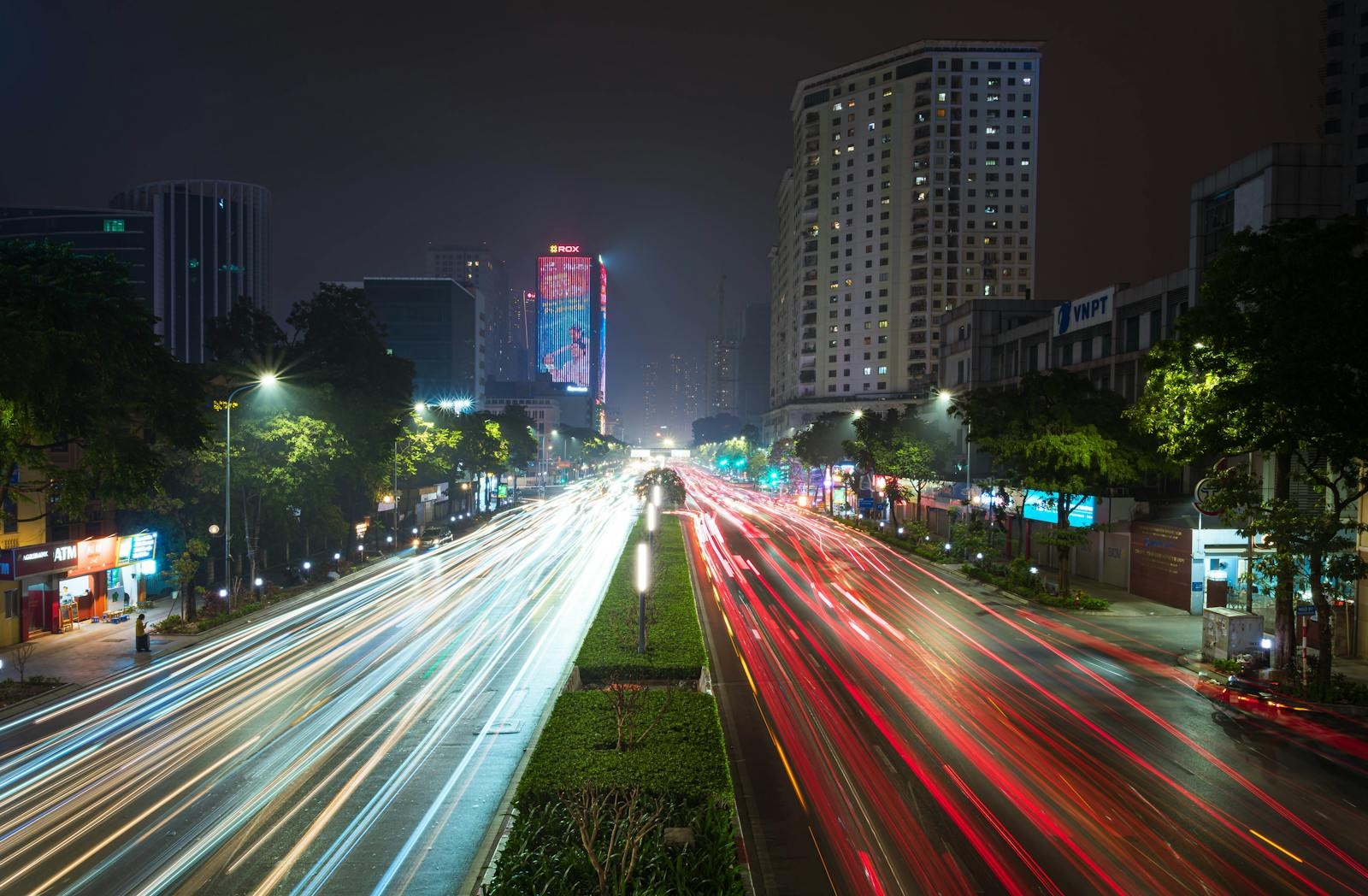 Dynamic urban evening scene with colorful car light trails on a bustling city street.