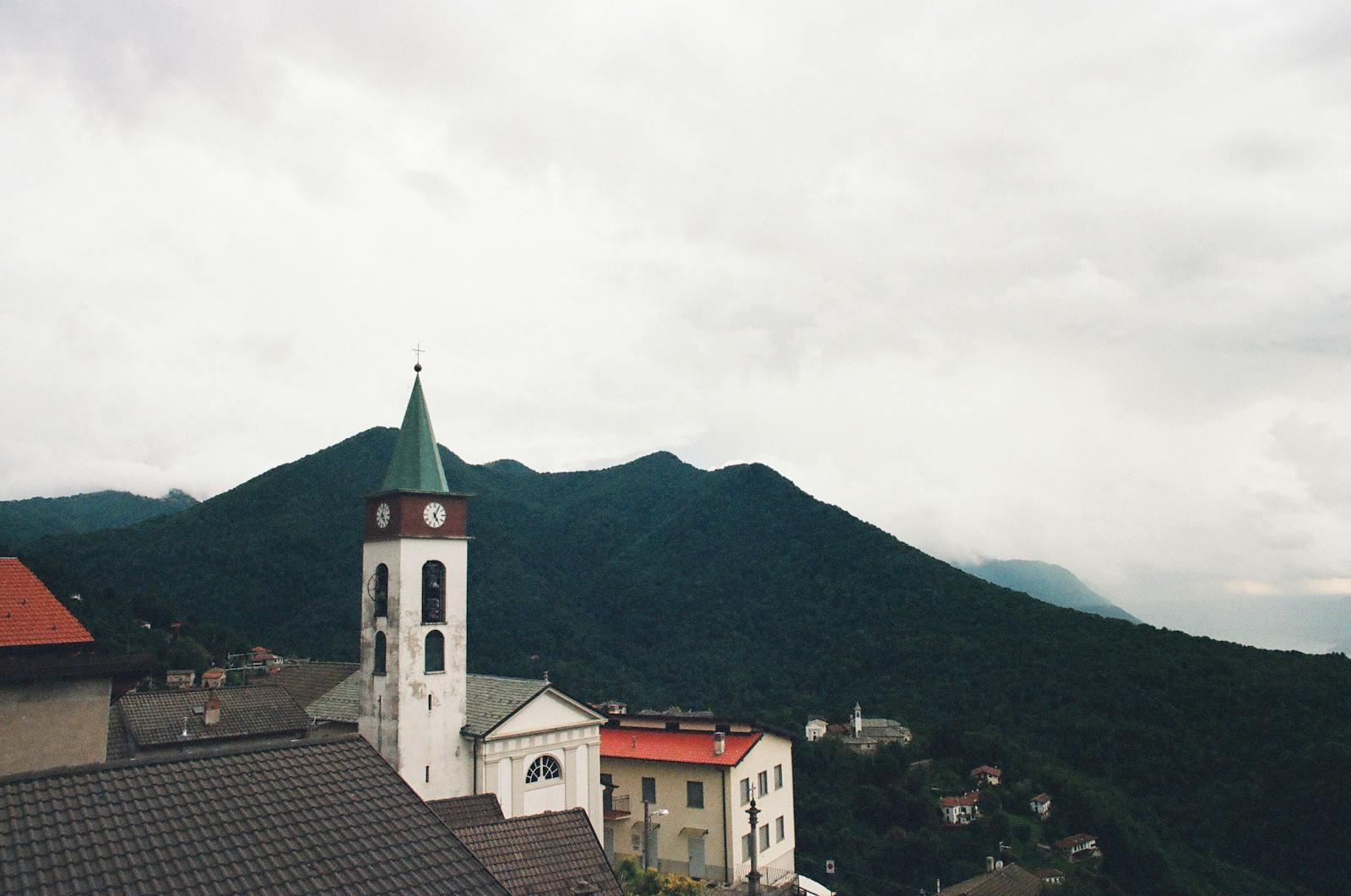 Charming Italian village with a church tower against mountain backdrop in Lombardia, Italy.