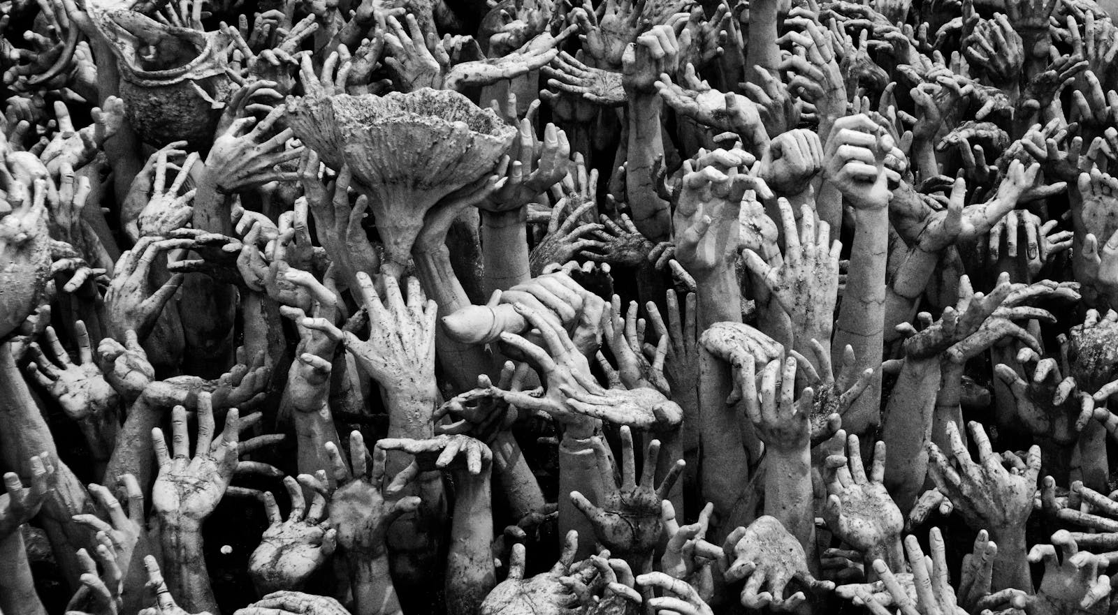 Intricate sculpture of reaching hands at Wat Rong Khun, symbolizing human suffering and desire.
