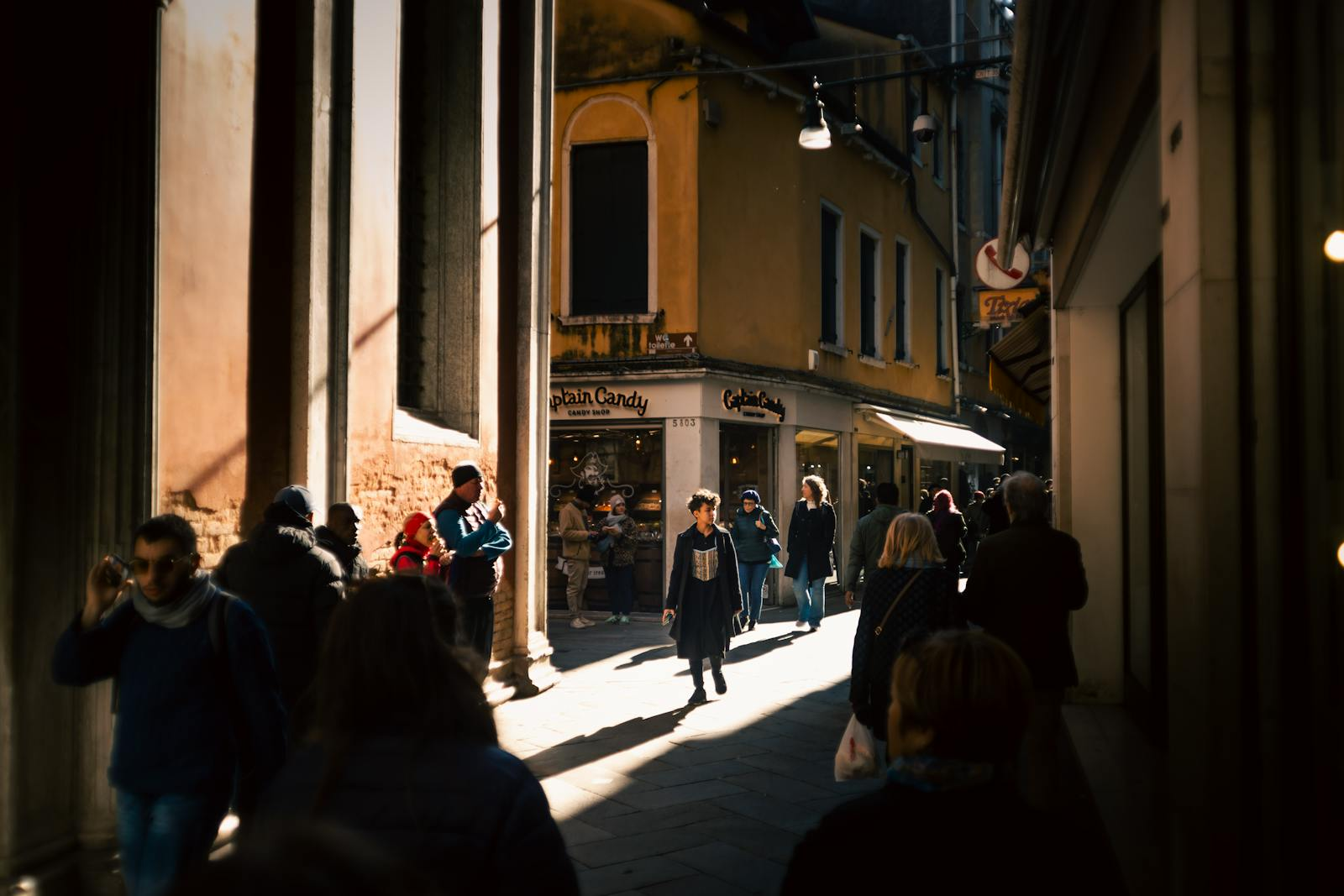 A vibrant urban alleyway bustling with diverse pedestrians under warm sunlight.