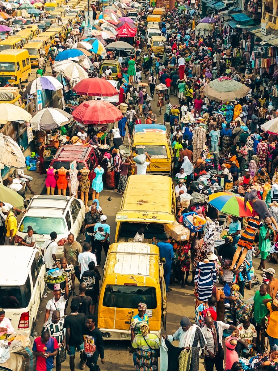 A bustling market in Lagos, Nigeria, with colorful umbrellas and busy streets filled with people and vehicles.