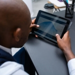 Corporate professional analyzing data and graphs on digital tablet in modern office setting.