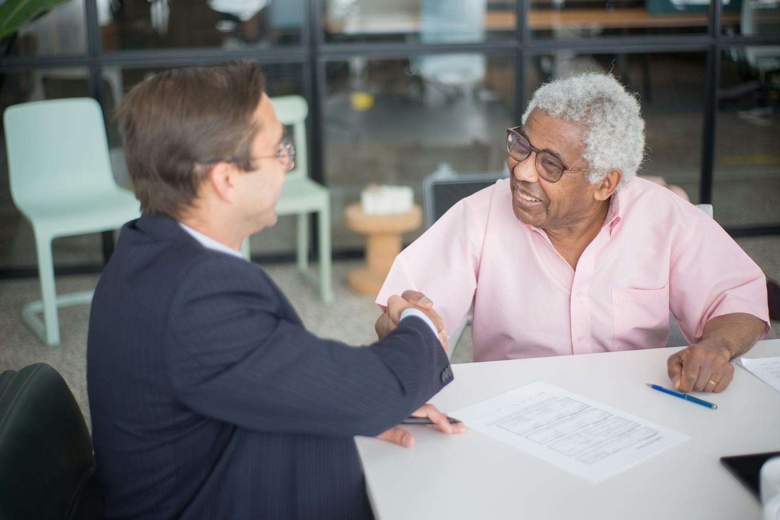 Two businessmen shaking hands in an office, sealing a deal.
