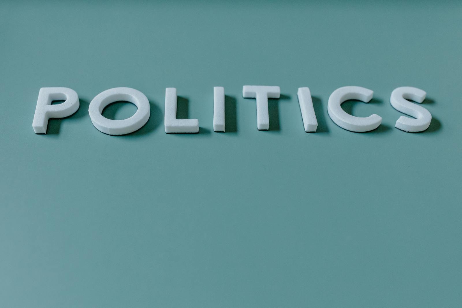 Close-up image of the word 'Politics' against a teal green background, highlighting political themes.