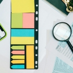 Colorful office supplies with smartphone and magnifying glass on tax forms. Perfect for business and financial themes.