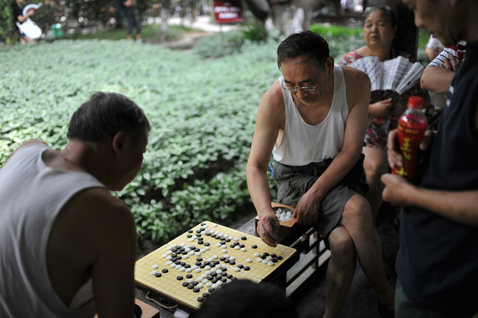 Men playing a board game outdoors with spectators