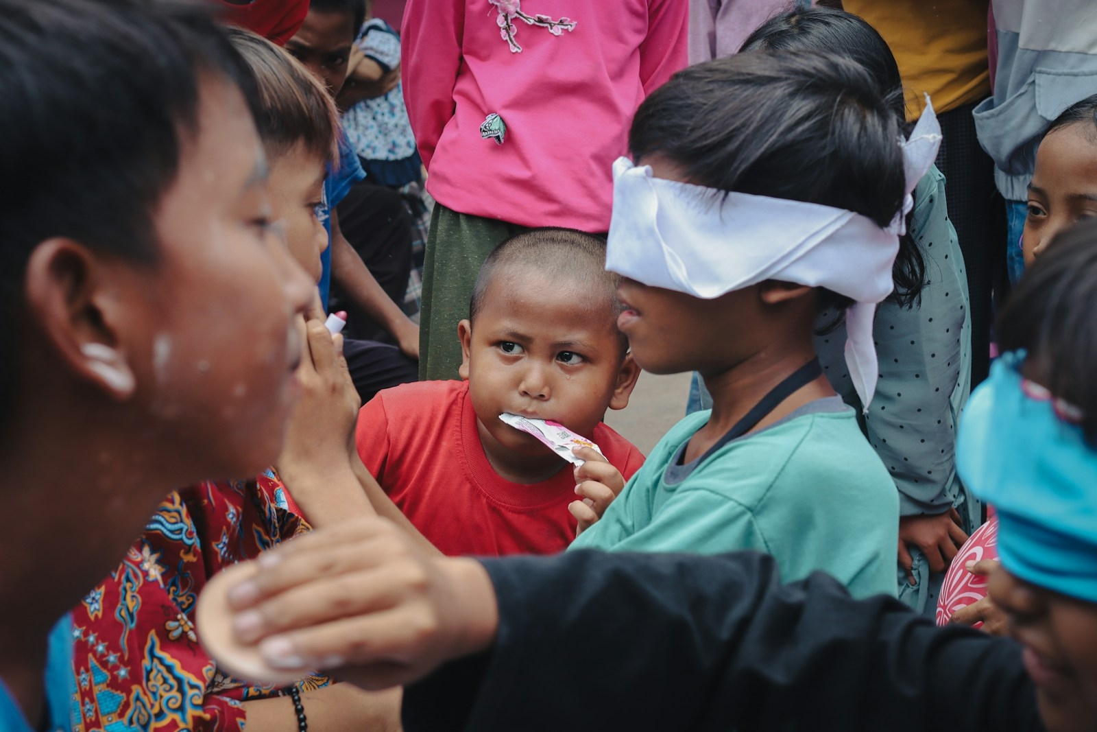 Children playing a blindfolded game with treats.