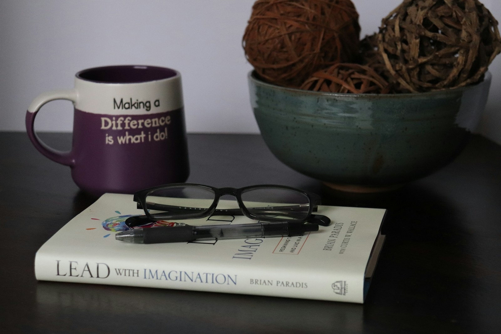 a book, glasses, and ball of yarn on a table